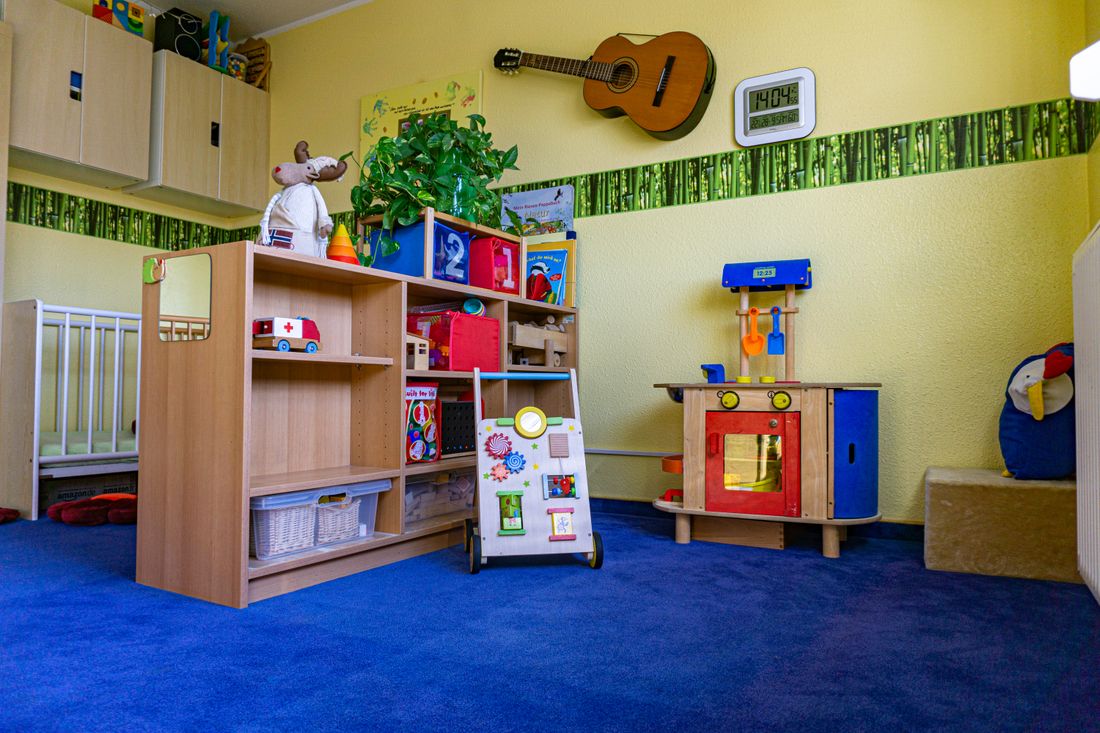 Spielecke mit Holzregal voller Spielsachen, Kinderküche und Lauflernwagen