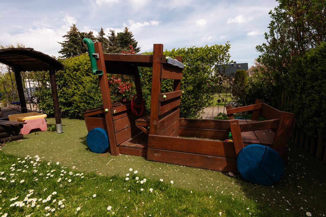 Spielauto aus Holz mit rotem Lenkrad im Garten